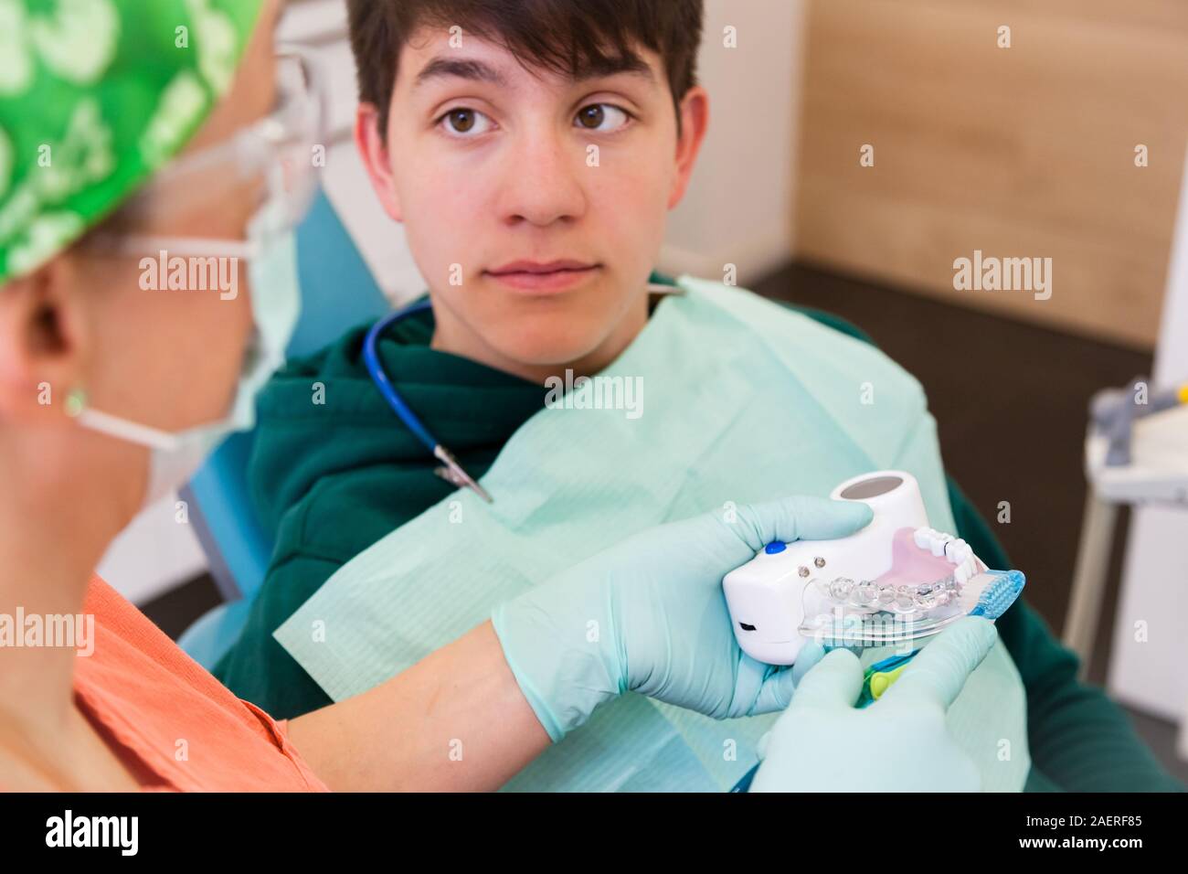 Close-up del giovane uomo in chirurgia dentale guardando al medico donna che sta mostrando come spazzolare i denti, cure dentarie concept Foto Stock