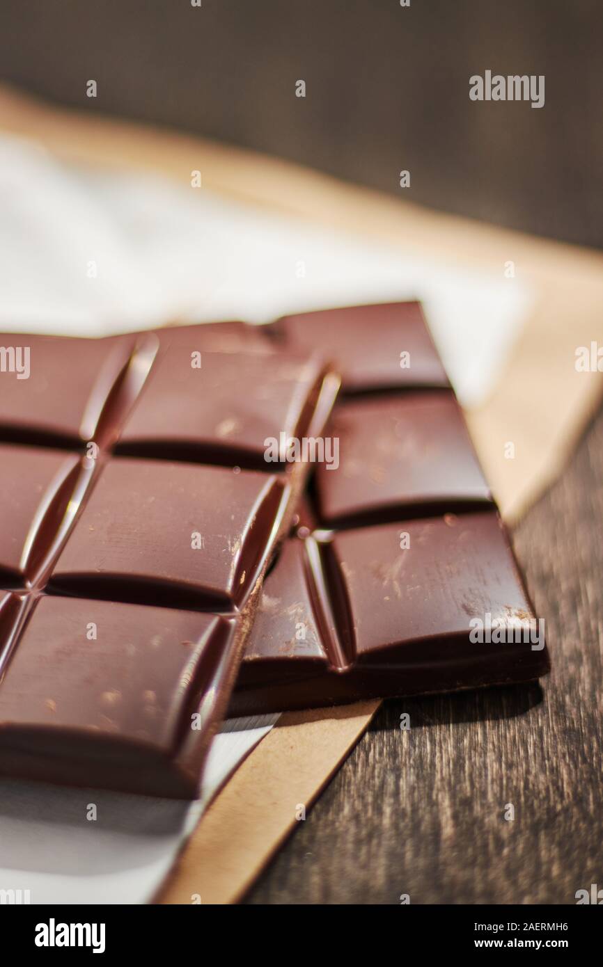 Cioccolato fondente in imballaggi di carta su un tavolo di legno. Foto Stock