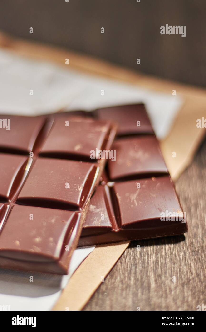 Cioccolato fondente in imballaggi di carta su un tavolo di legno. Foto Stock