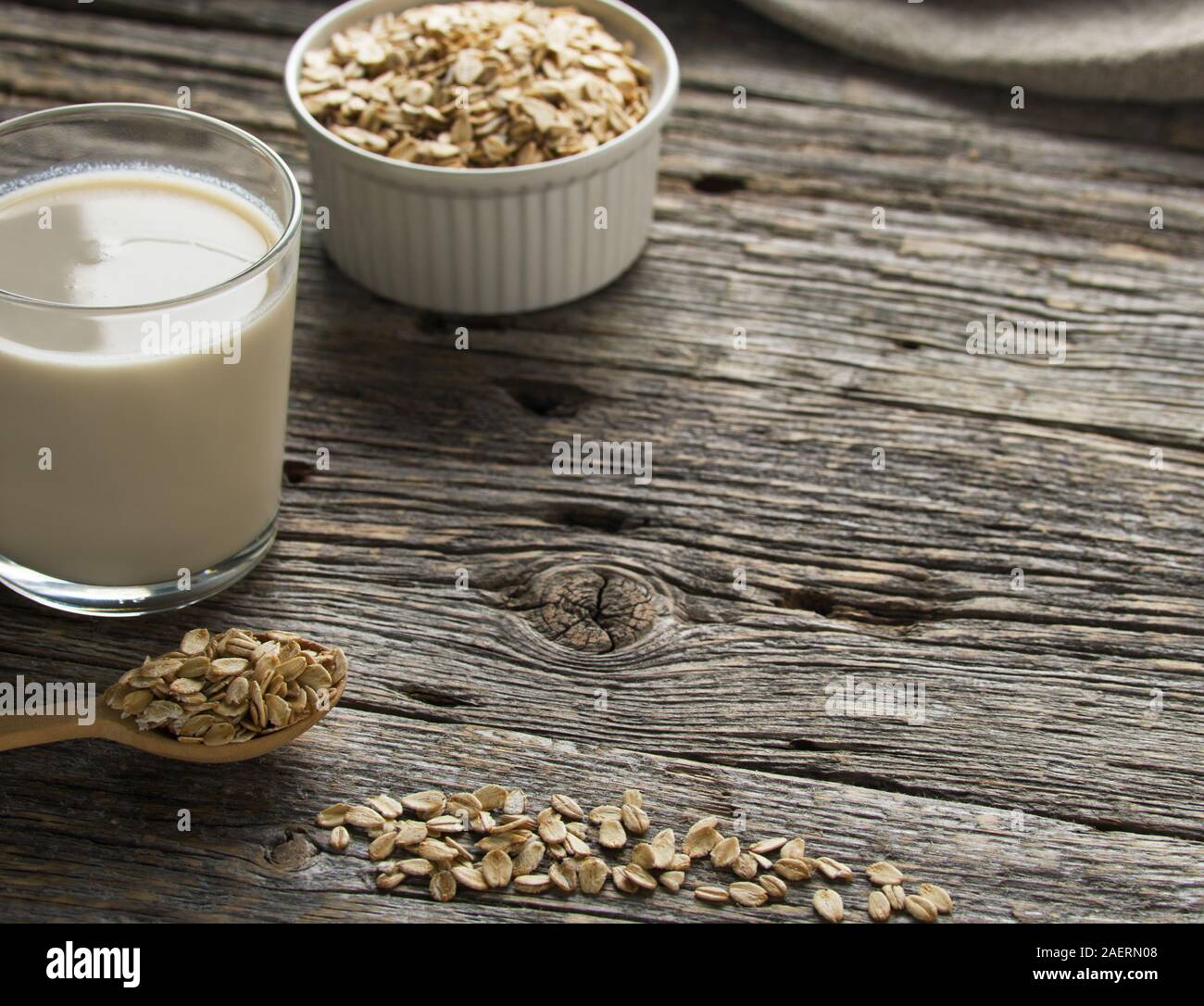 Latte d'avena fresco nel bicchiere da bere su sfondo di legno. Concetto di alimentazione sana con spazio di copia. Foto Stock
