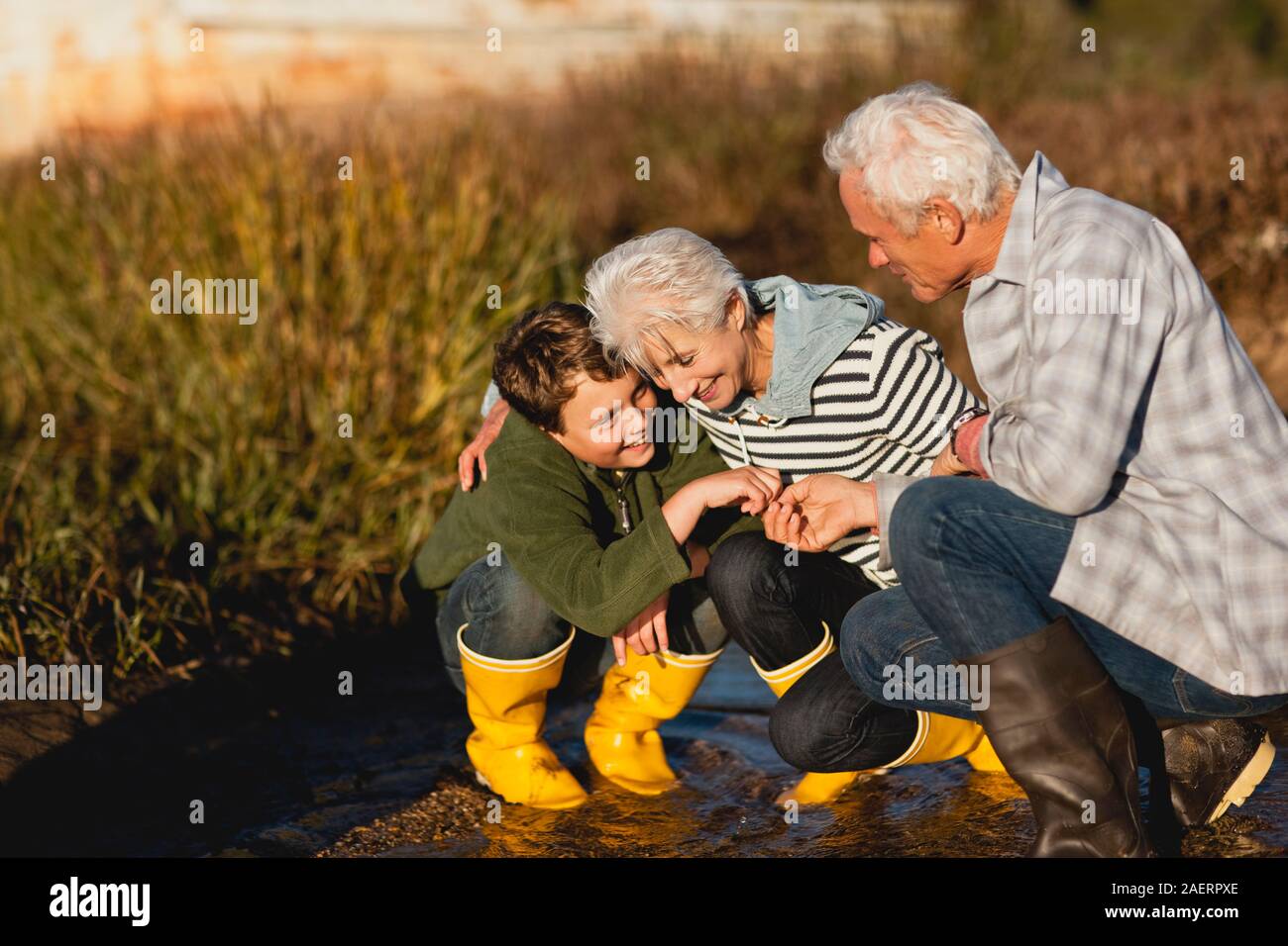 Ragazzo e i suoi nonni sorriso e parlare di come essi crouch insieme su un percorso di cotto. Foto Stock