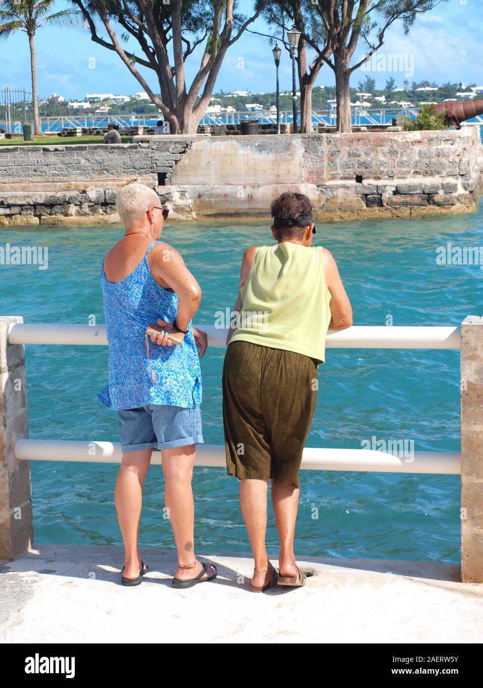 Madre e figlia cerca su parapetto in San Giorgio a Bermuda. Apparire in una profonda discussione e godendo di ogni altri società. Foto Stock
