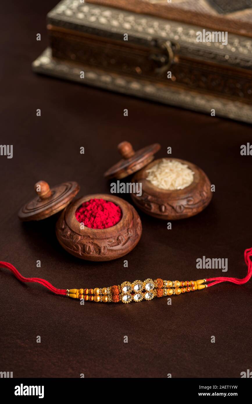 Festival indiano: Raksha Bandhan sfondo con un elegante Rakhi, grani di riso e Kumkum. Un tradizionale indiano fascia da polso che è un simbolo di amore Foto Stock