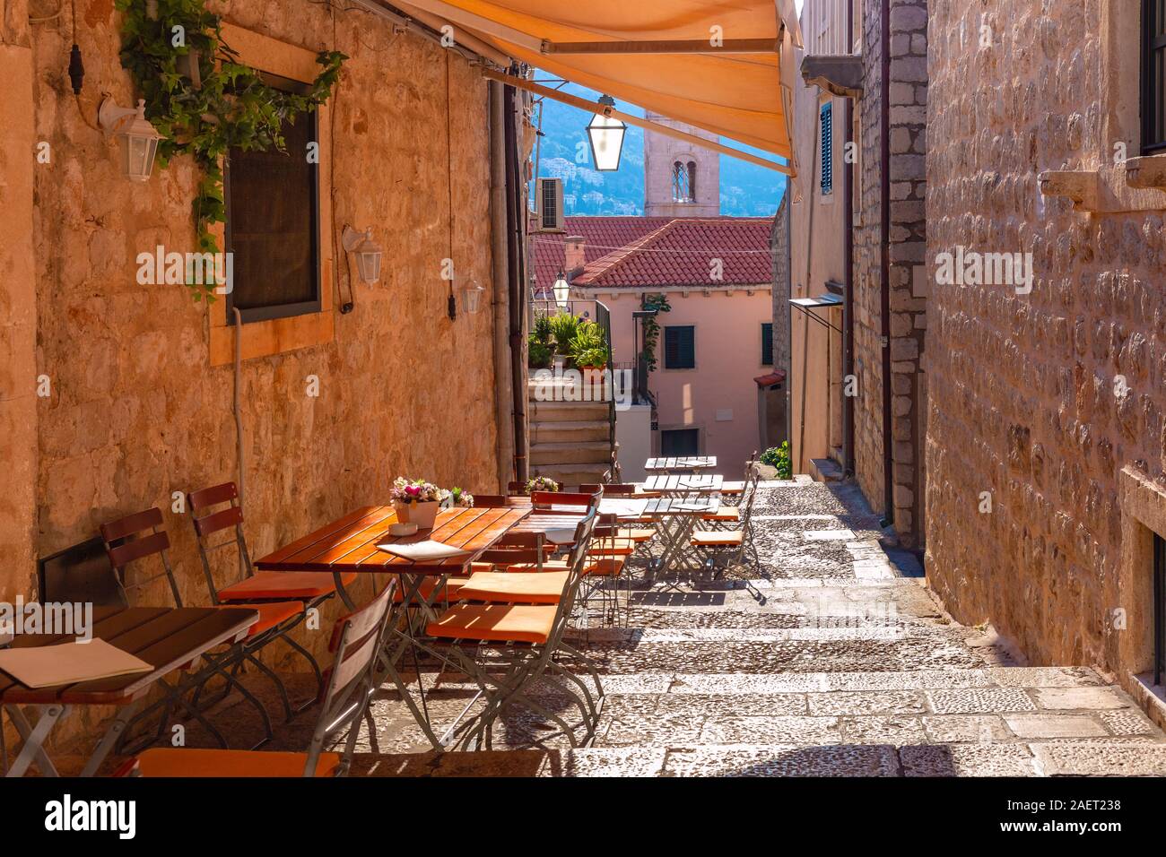 Via medievale con scale e cafe tabelle nella famosa città europea di Dubrovnik in una giornata di sole. Foto Stock