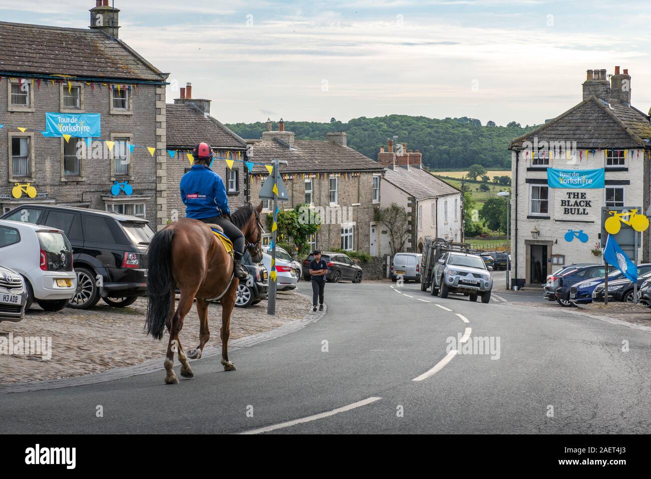 Middleham, Inghilterra - un gruppo di equestrians cavalcare lungo un piccolo villaggio street, Yorkshire, Regno Unito Foto Stock