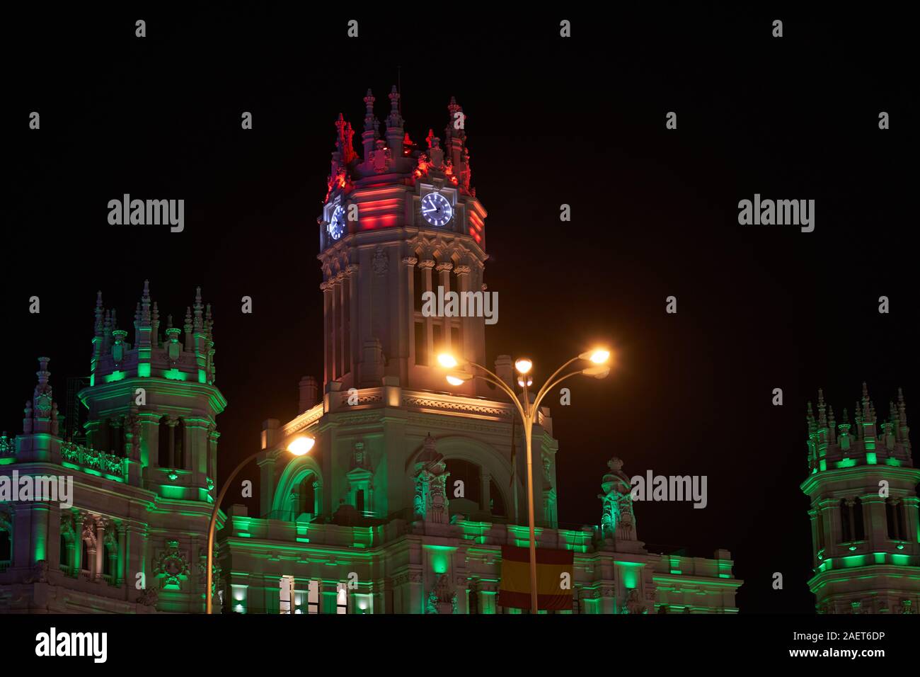 La torre dell'orologio del Palazzo delle comunicazioni a Cibeles a Madrid, illuminato in diversi colori per il Natale 2019 Foto Stock