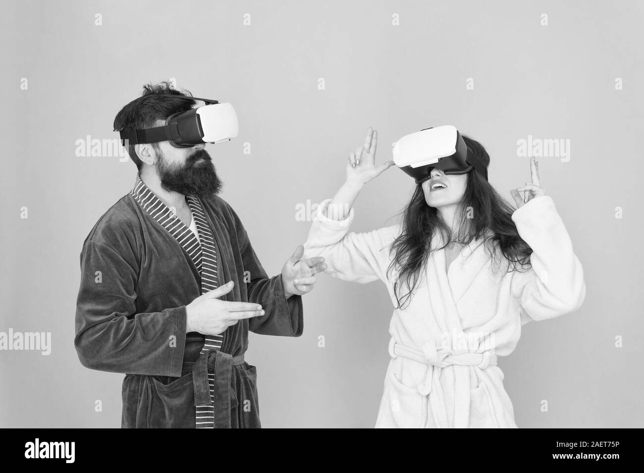 Famiglia giovane indossare occhiali vr. ragazza e uomo hipster rilassarsi in accappatoio. al mattino con la tecnologia del futuro. Un altra realtà è qui. Innovazione in famiglia. Creare la vostra realtà. mondo della fantasia. Foto Stock