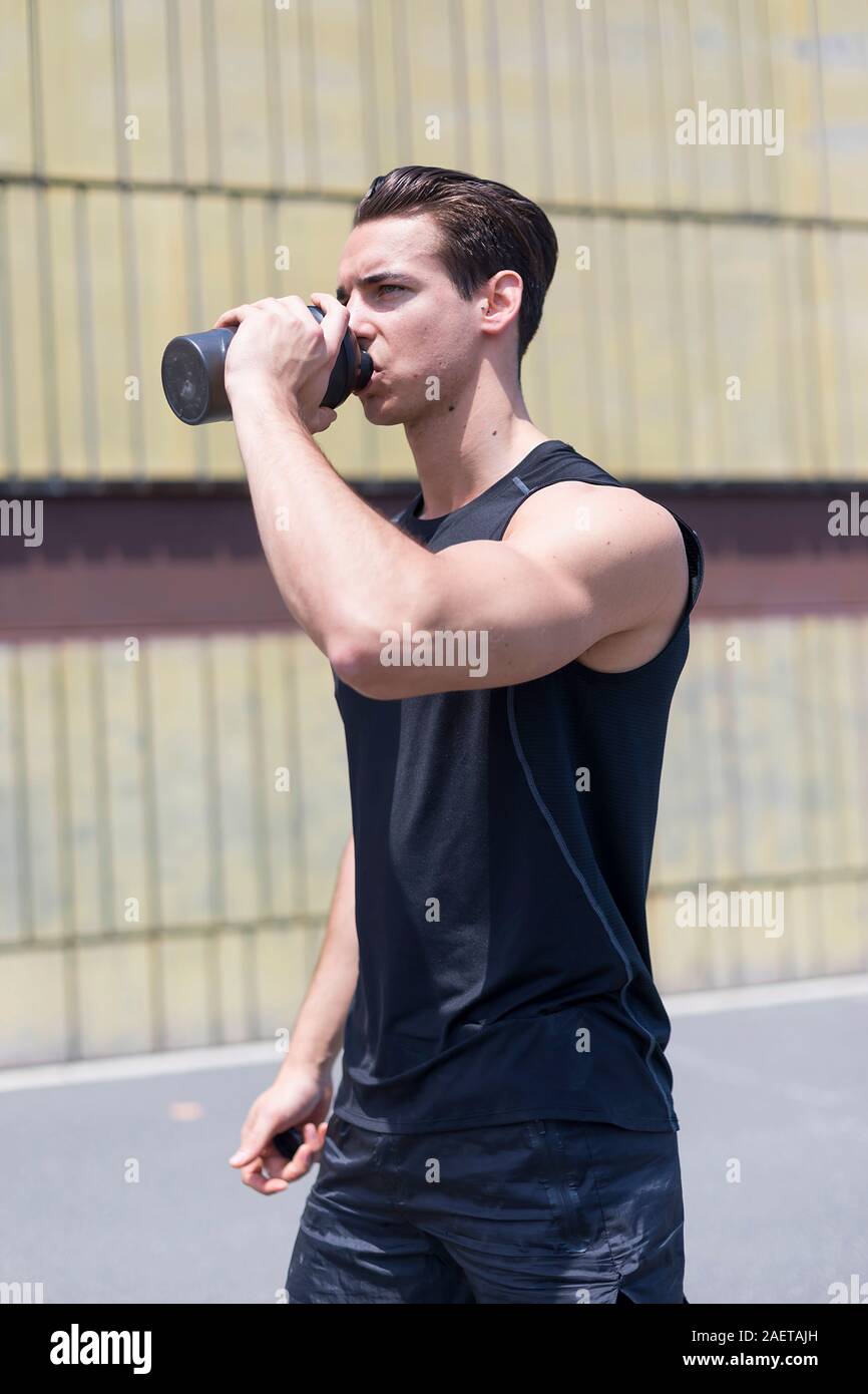 Giovane atleta acqua potabile dopo il jogging Foto Stock