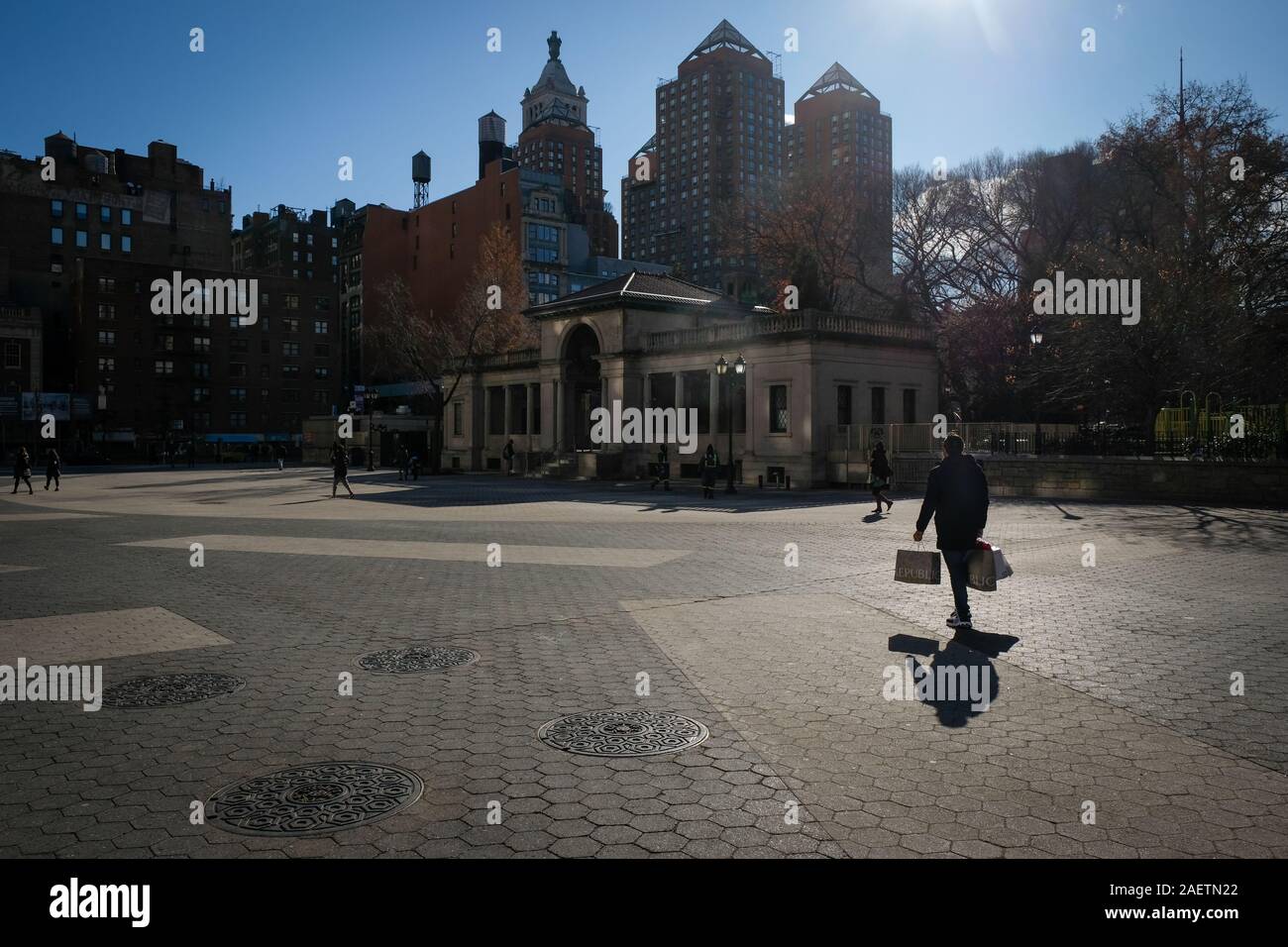 Uomo con shopping bags passi attraverso la Union Square di New York City. Foto Stock