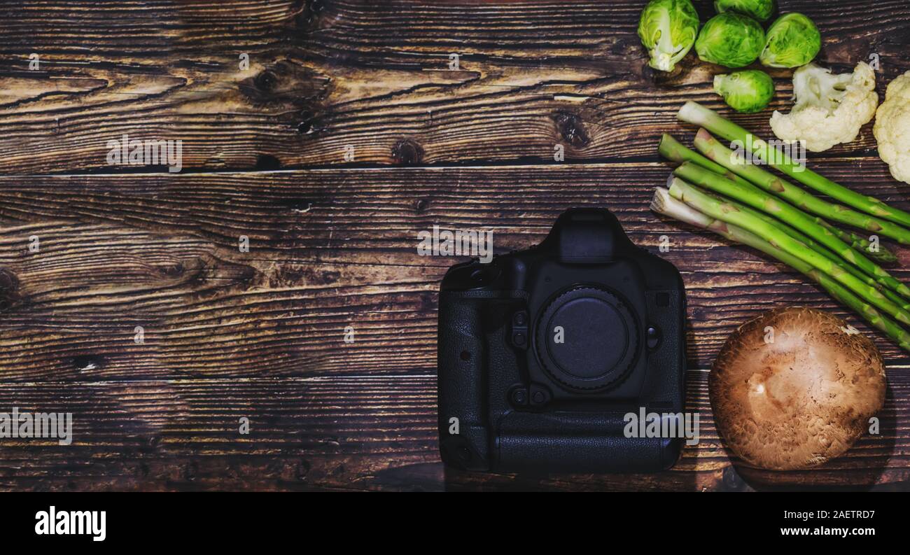 Fotocamera e verdure su sfondo di legno, come un concetto di fotografia di cibo. Creative quadro concettuale per piatti professionali fotografi, socia Foto Stock
