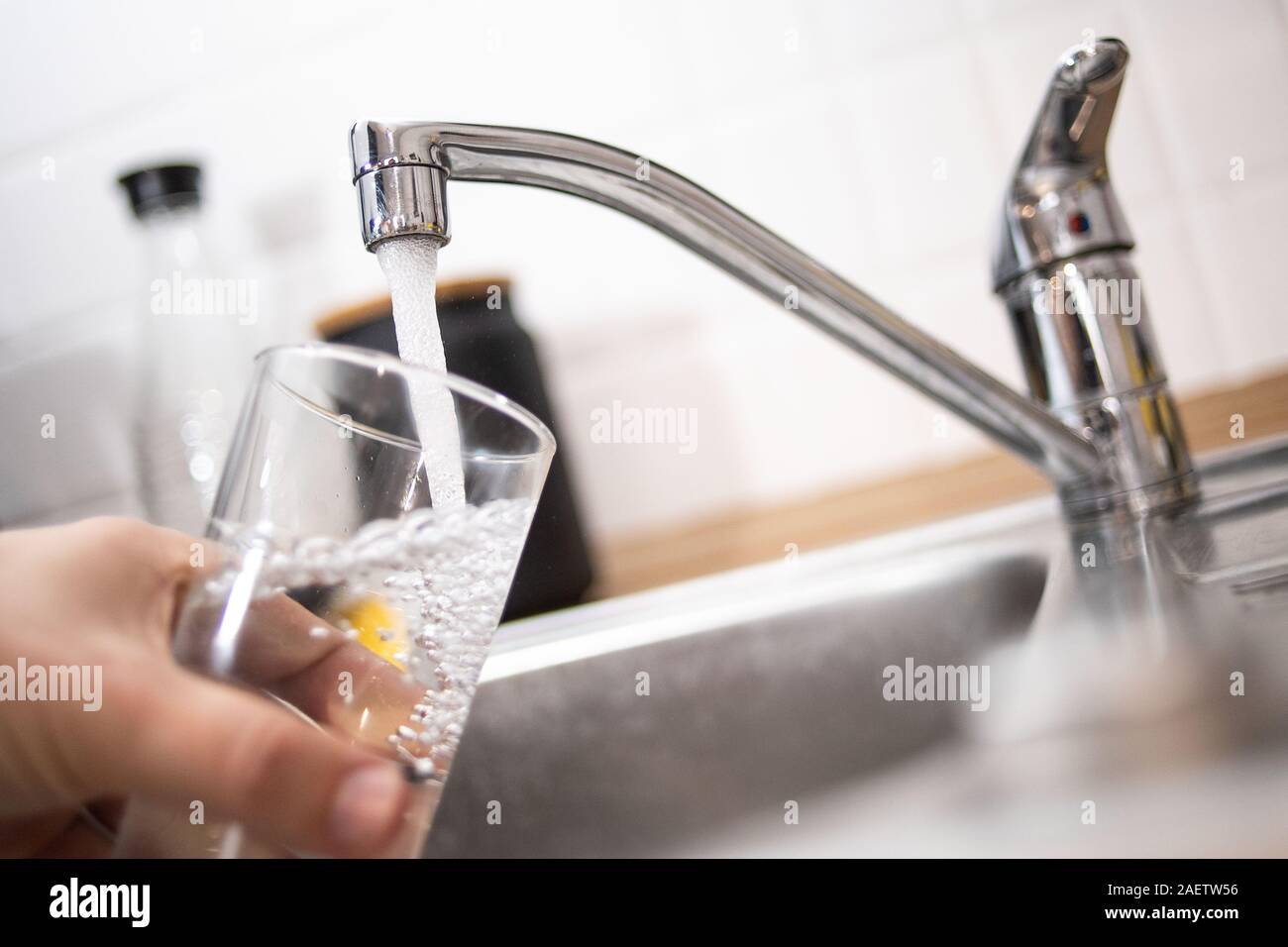 Duesseldorf, Germania. Decimo Dec, 2019. Illustrazione - un uomo tiene un bicchiere sotto l'acqua corrente. Il Bündnis 90/Die Grünen i commenti del gruppo sulla base dei risultati di un'inchiesta sull'acqua nel NRW. Una delle questioni in gioco è lo sviluppo di acqua per uso domestico di consumo. Credito: Marius Becker/dpa/Alamy Live News Foto Stock