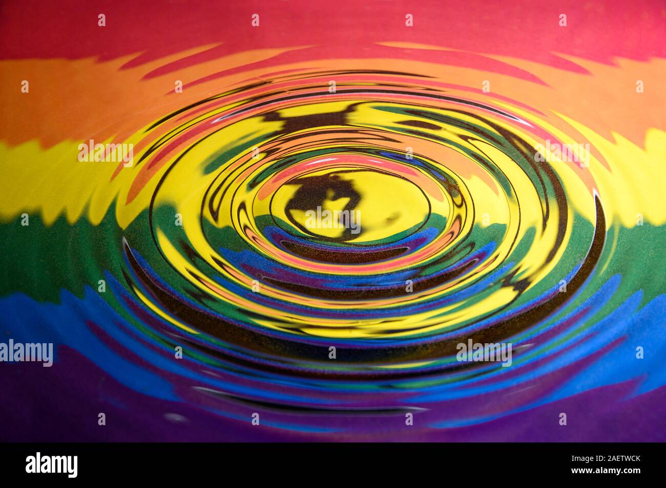 Increspature circolari su una superficie di acqua che riflette il Gay Pride estinzione bandiera di ribellione e logo. Estinzione astratto Gay Pride sfondo Foto Stock