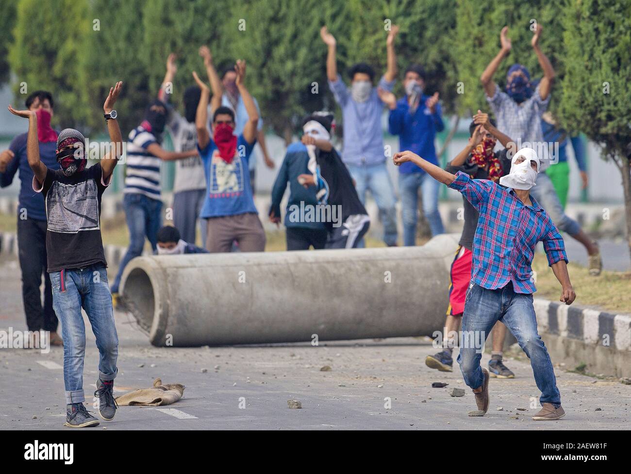 Un musulmano del Kashmir protester getta pietre alle truppe indiane come altri gridare pro libertà slogan in Srinagar, Indiano Kashmir controllato Foto Stock