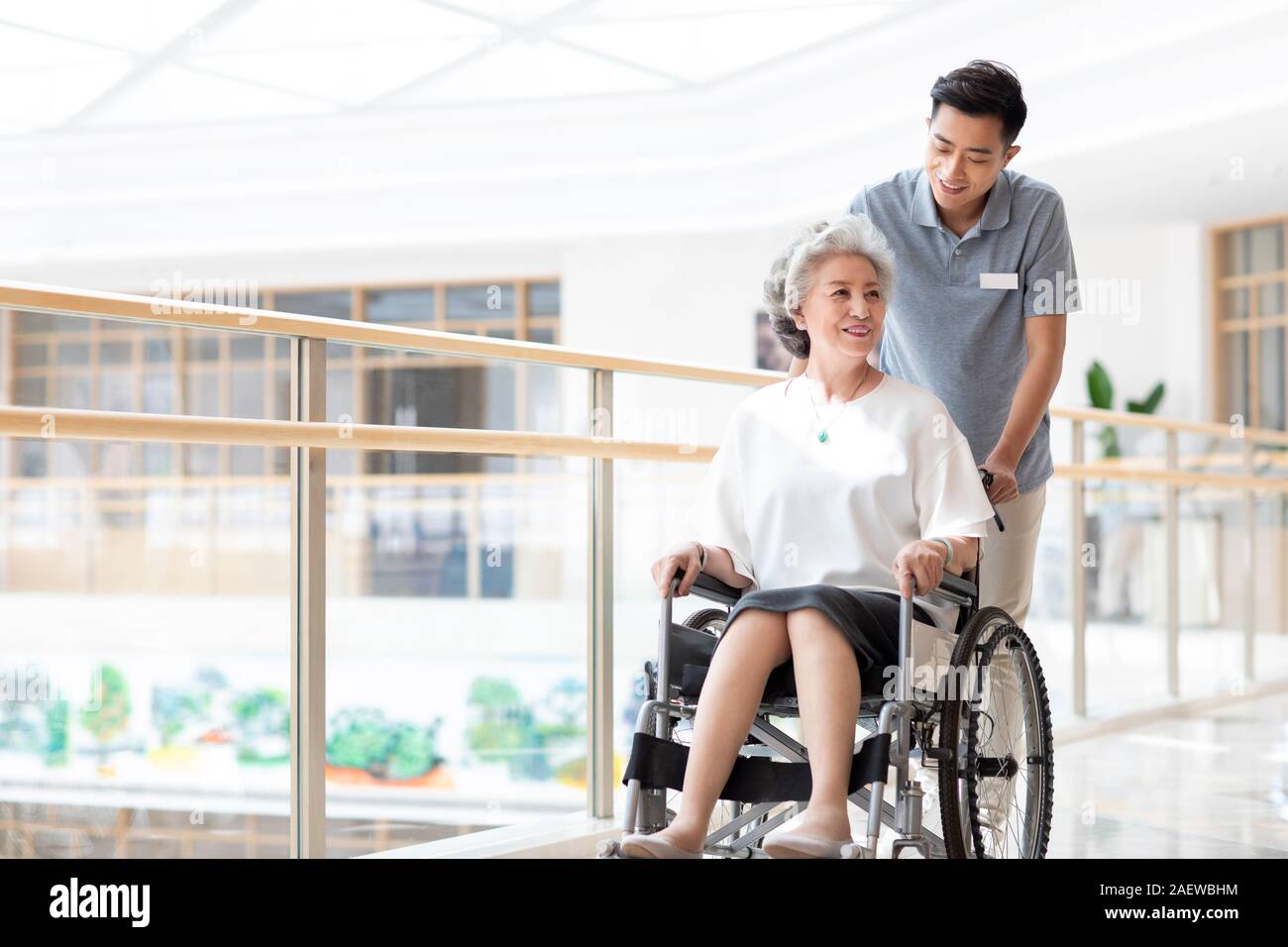 Assistente infermieristica avendo cura di senior donna in sedia a rotelle Foto Stock