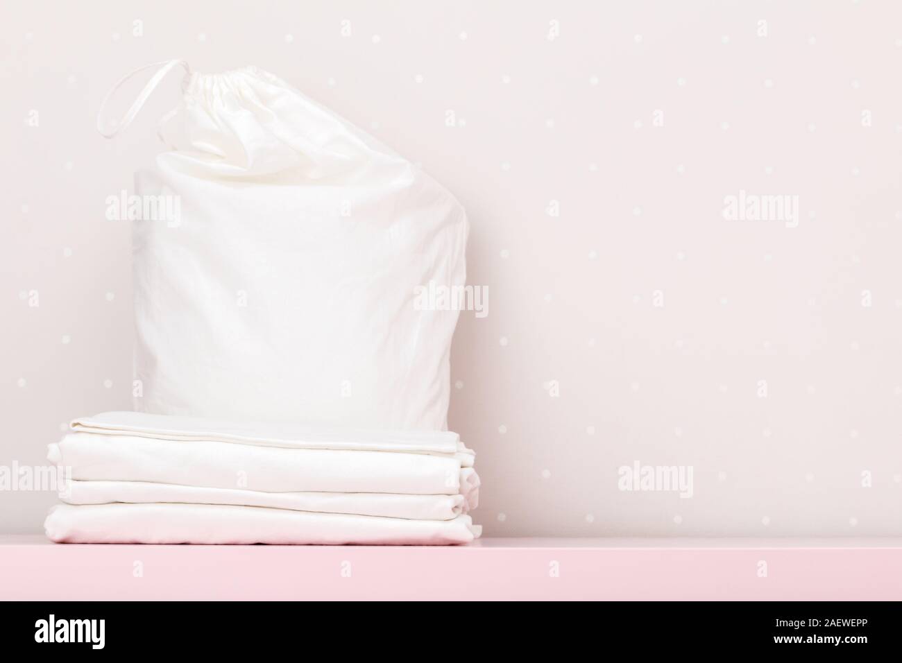 Biancheria da letto pulita e un foglio sacchetto custodia. Pila su un muro bianco sullo sfondo. Foto Stock