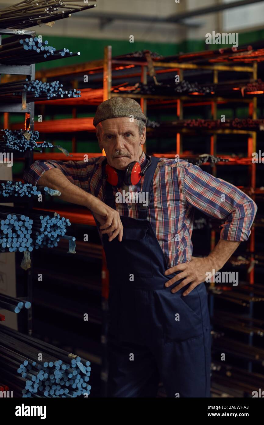 Ritratto di coppia meccanico tute in piedi vicino a tubi di metallo e guardando la telecamera in magazzino Foto Stock