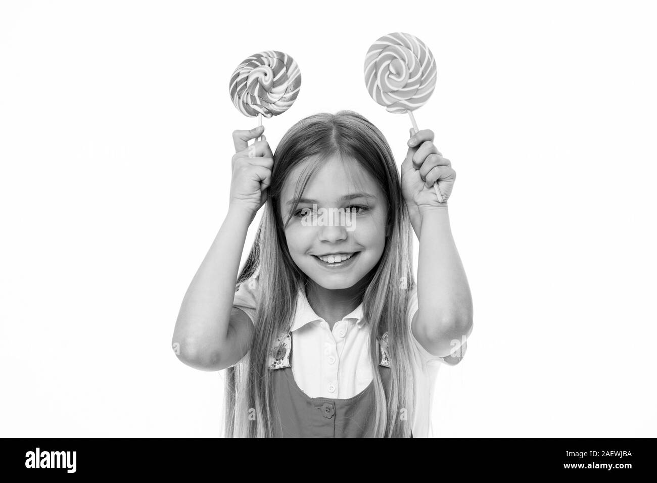 Funny Girl sorridente con caramelle di turbolenza. Capretto piccolo sorriso con caramelle su bastoni isolato su bianco. Dolce e molto grande. Bambino felice sorriso con connettori lollipop. Cibo e dessert. La dieta e dieta. Foto Stock