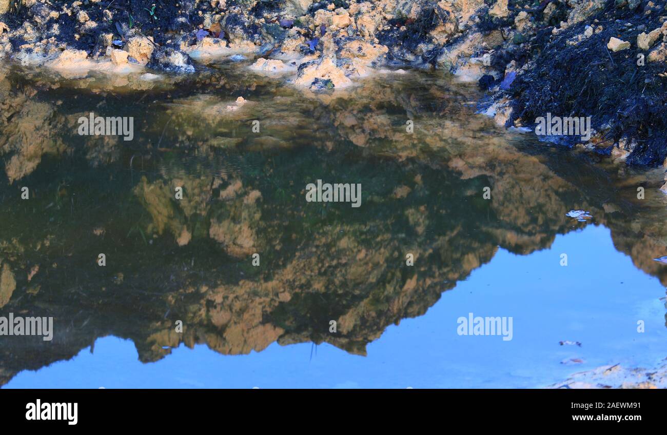 Argilla gialla è riflessa in una pozza Foto Stock