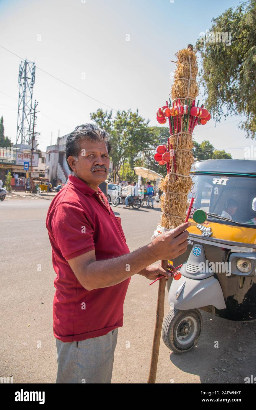 AMRAVATI, Maharashtra, India, gennaio - 26, 2018: Unidentified venditore ambulante che vende colorato artigianali tradizionali baby sonaglio (mini drum) giocattolo. Zone rurali Foto Stock