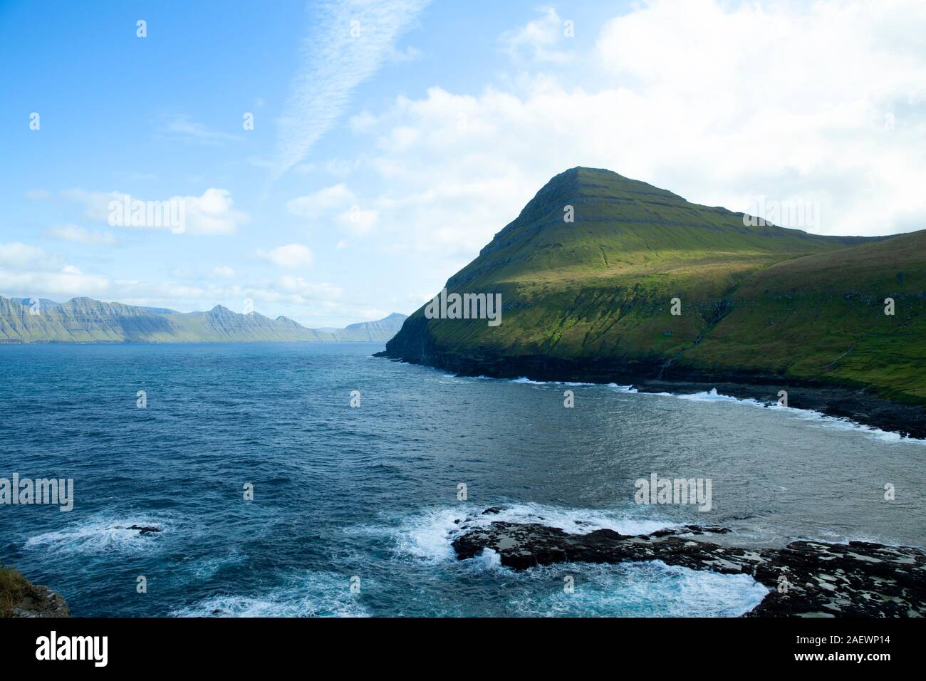 Sulle montagne circostanti e sul mare vicino a Gjogv con Kalsoy isola sullo sfondo Foto Stock