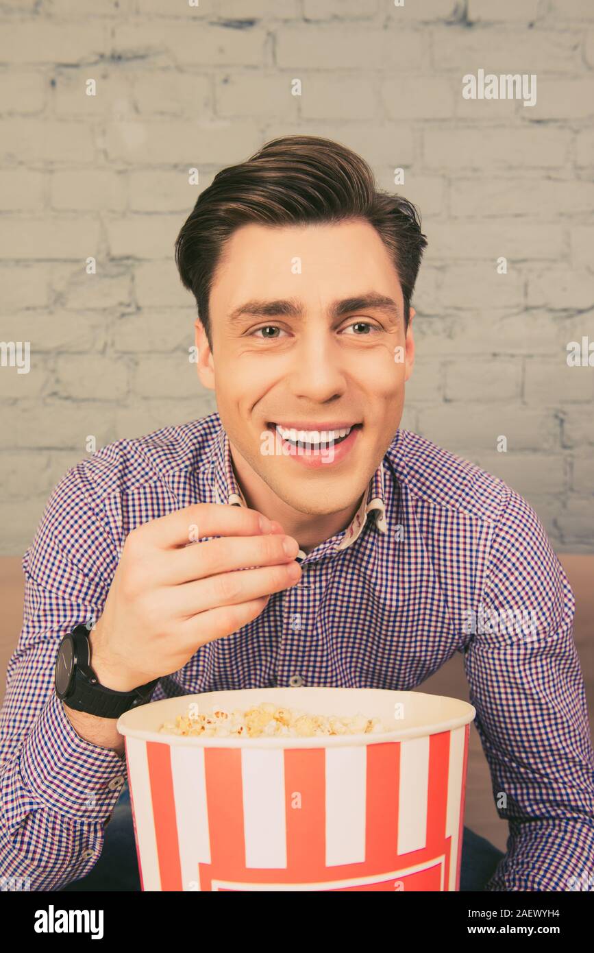 Ritratto di felice uomo sorridente mangiare popcorn a casa Foto Stock