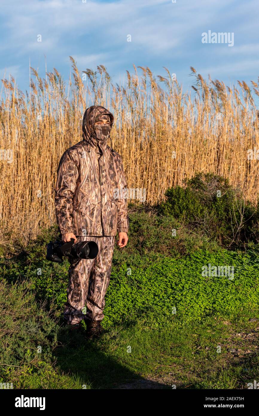Fotografo naturalista in azione, con mimetizzazione e fotocamera, nel deserto. Foto Stock
