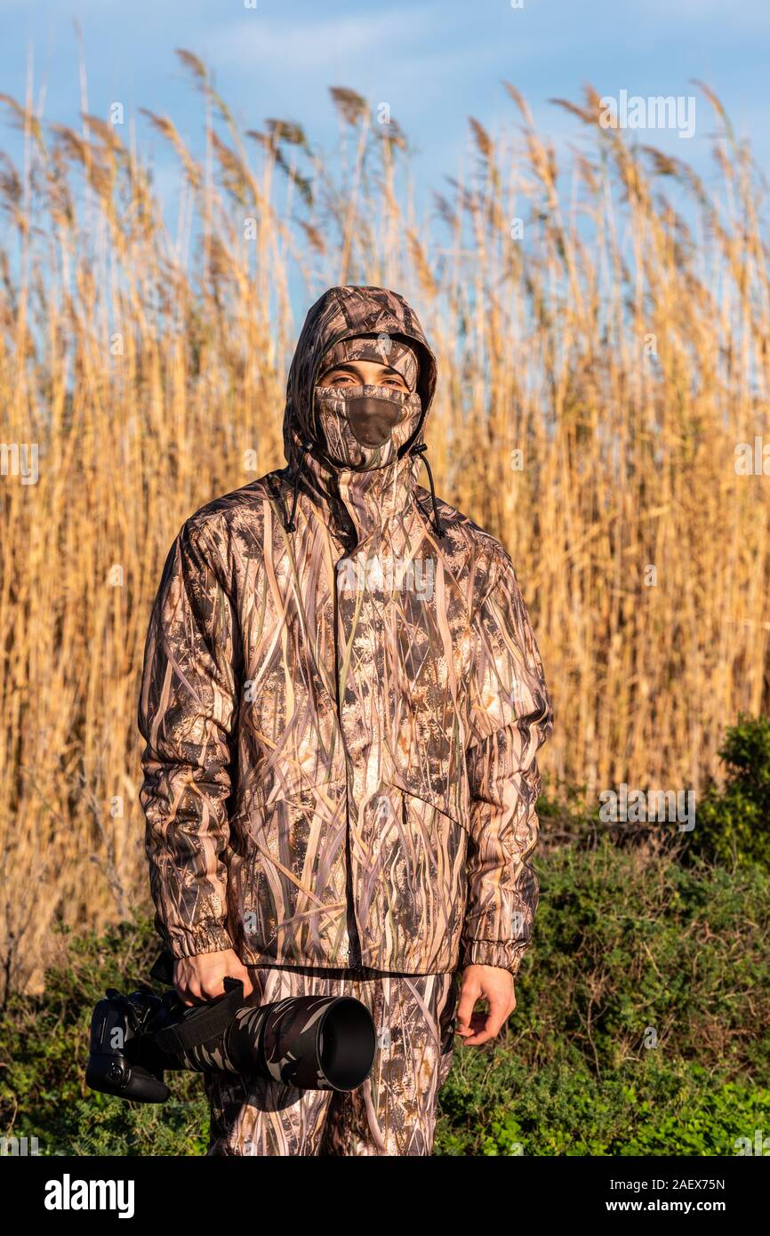 Fotografo naturalista in azione, con mimetizzazione e fotocamera, nel deserto. Foto Stock