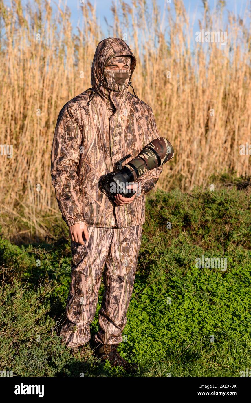 Fotografo naturalista in azione, con mimetizzazione e fotocamera, nel deserto. Foto Stock