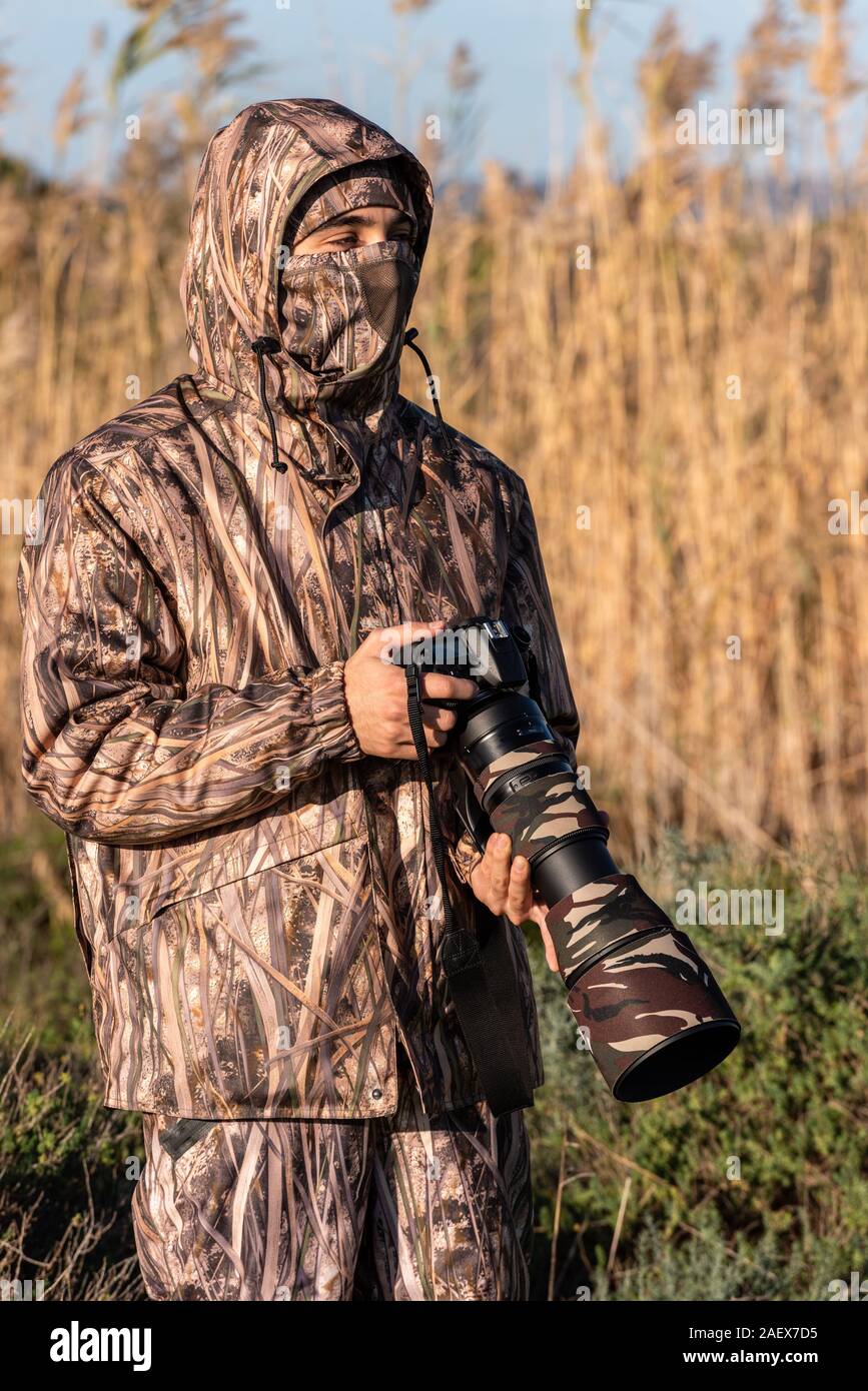 Fotografo naturalista in azione, con mimetizzazione e fotocamera, nel deserto. Foto Stock