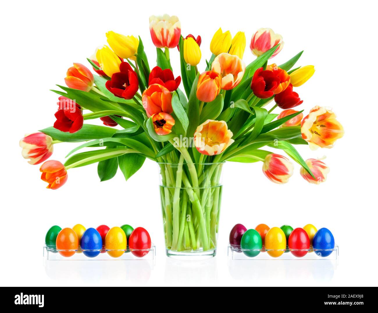 Splendida colorato bouquet di tulipani in un vaso di vetro con le uova di Pasqua su entrambi i lati, isolato su bianco Foto Stock