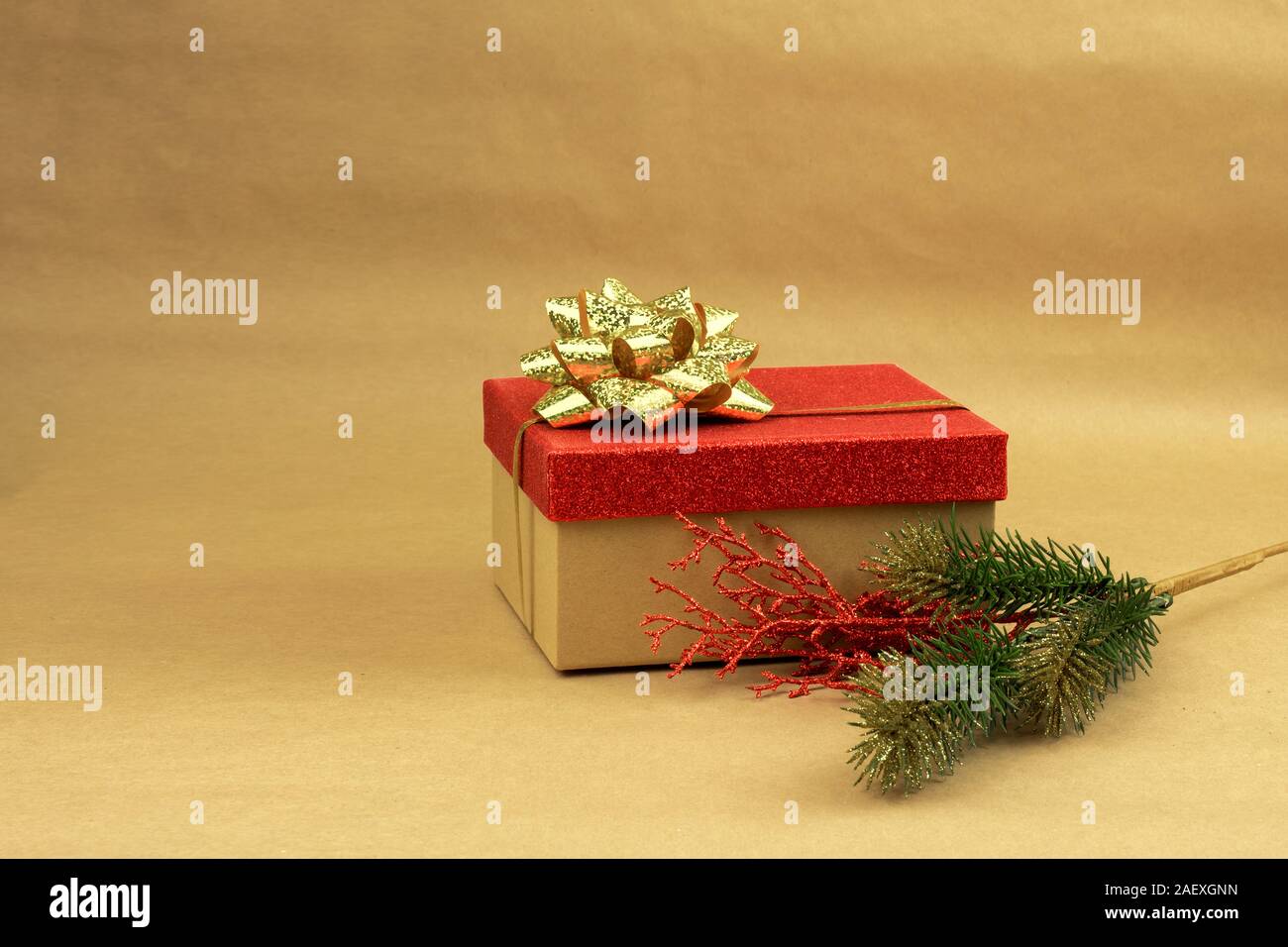Confezione regalo con coperchio rosso e oro prua con un ramo di albero di Natale su sfondo marrone Foto Stock