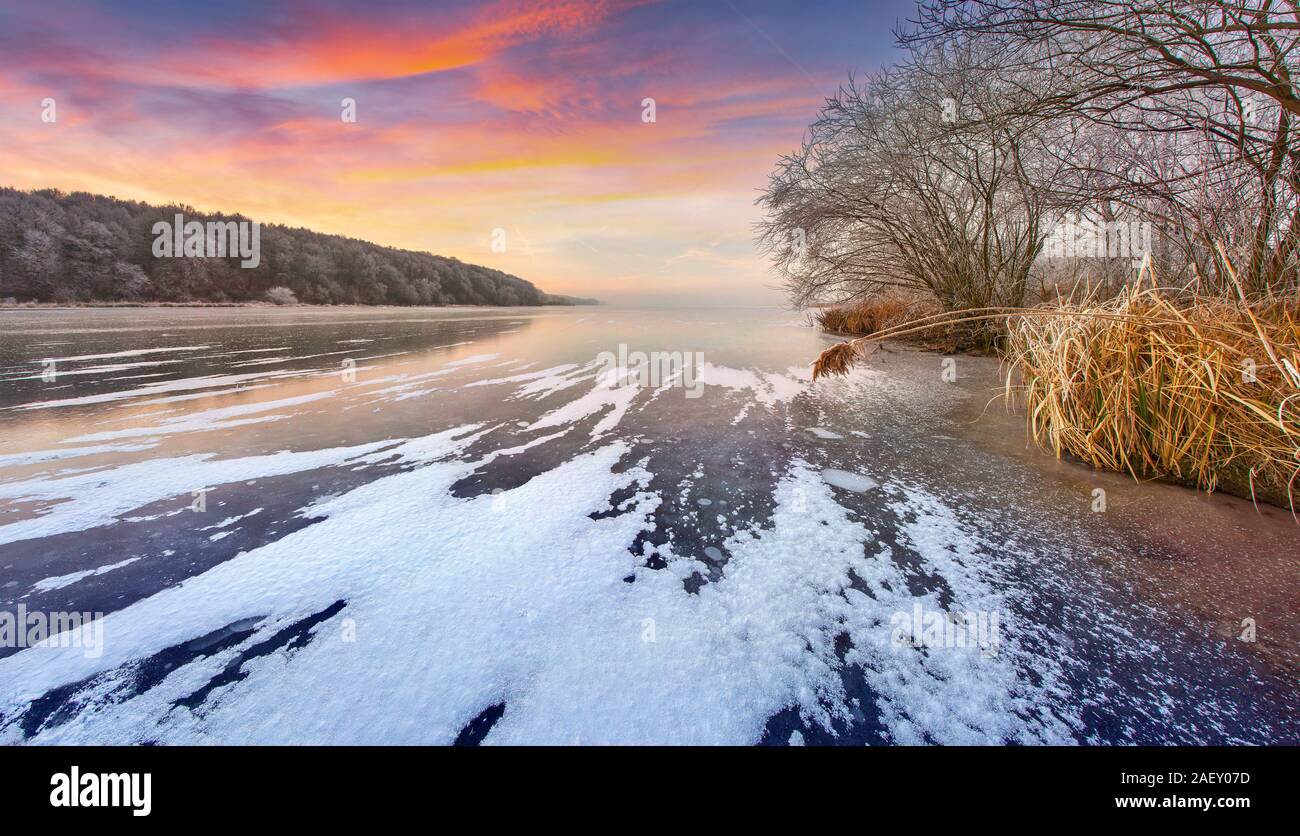 Suggestivo tramonto in inverno sul lago ghiacciato. Colorata scena all'aperto. Stile artistico post elaborati foto. Foto Stock