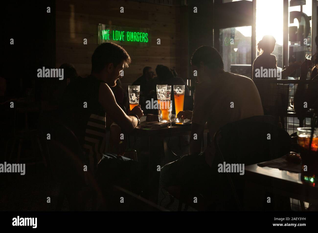 Un paio di ragazzi pf è visto bere birra in spagnolo un Burger place al tramonto. Foto Stock