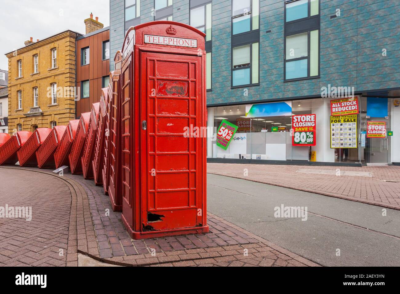 Una fila di inclinazione iconico cabine telefoniche a Londra con qualche edificio colorato come sfondo. Foto Stock