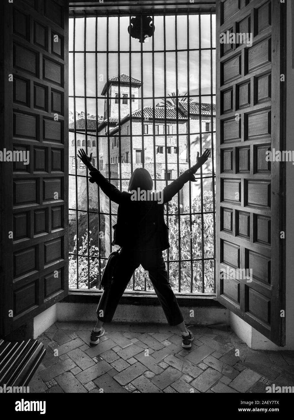 Vista posteriore di una donna di fronte a una finestra al Nasrid Palace, Alhambra di Granada, provincia di Granada, Spagna Foto Stock
