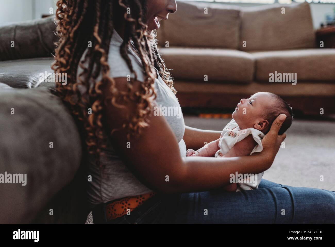 Multirazziale bambino nel giro di sorridere mom etnico con trecce Foto Stock
