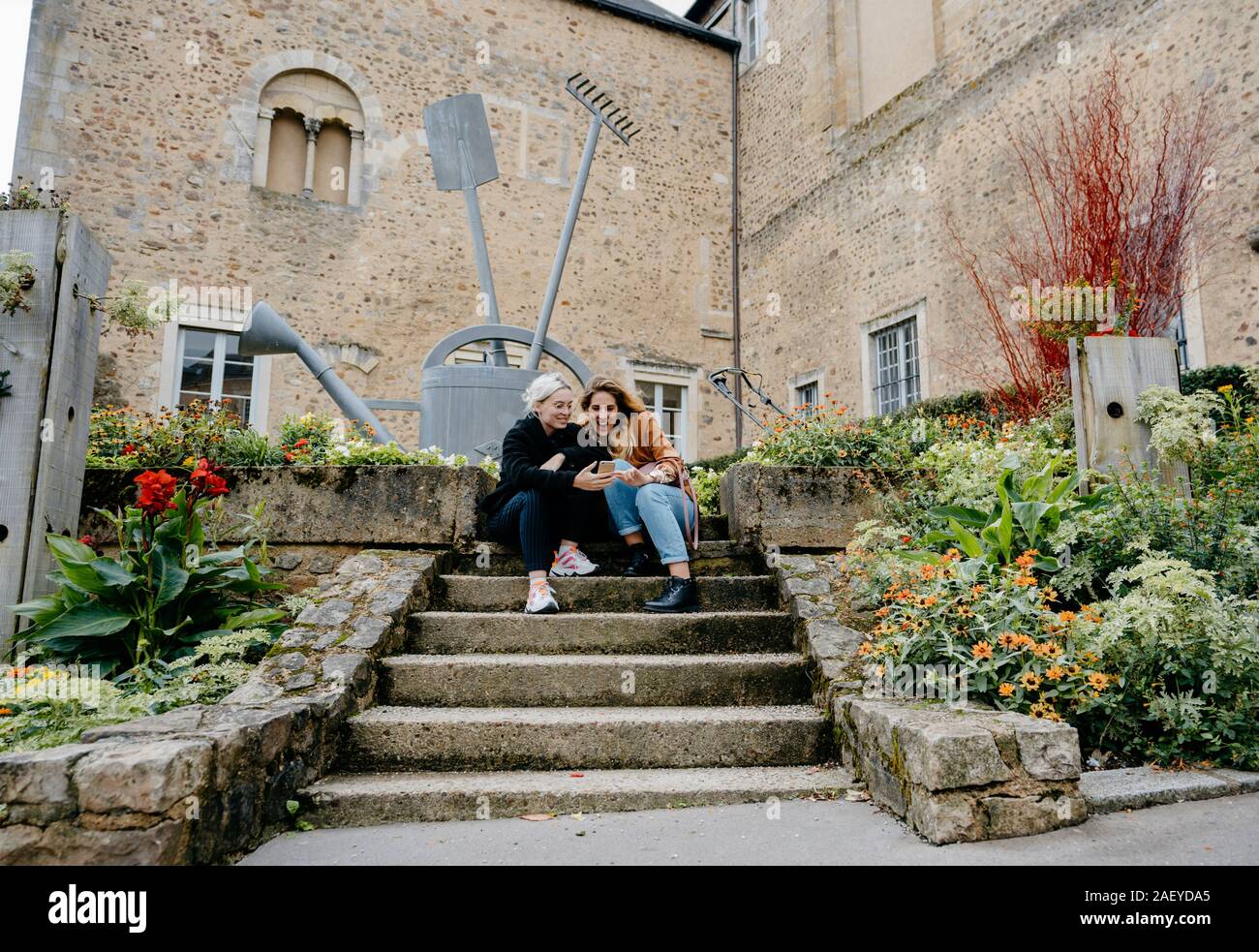 Giovani donne utilizzando il proprio smartphone sitted su scale in una cittadina francese Foto Stock