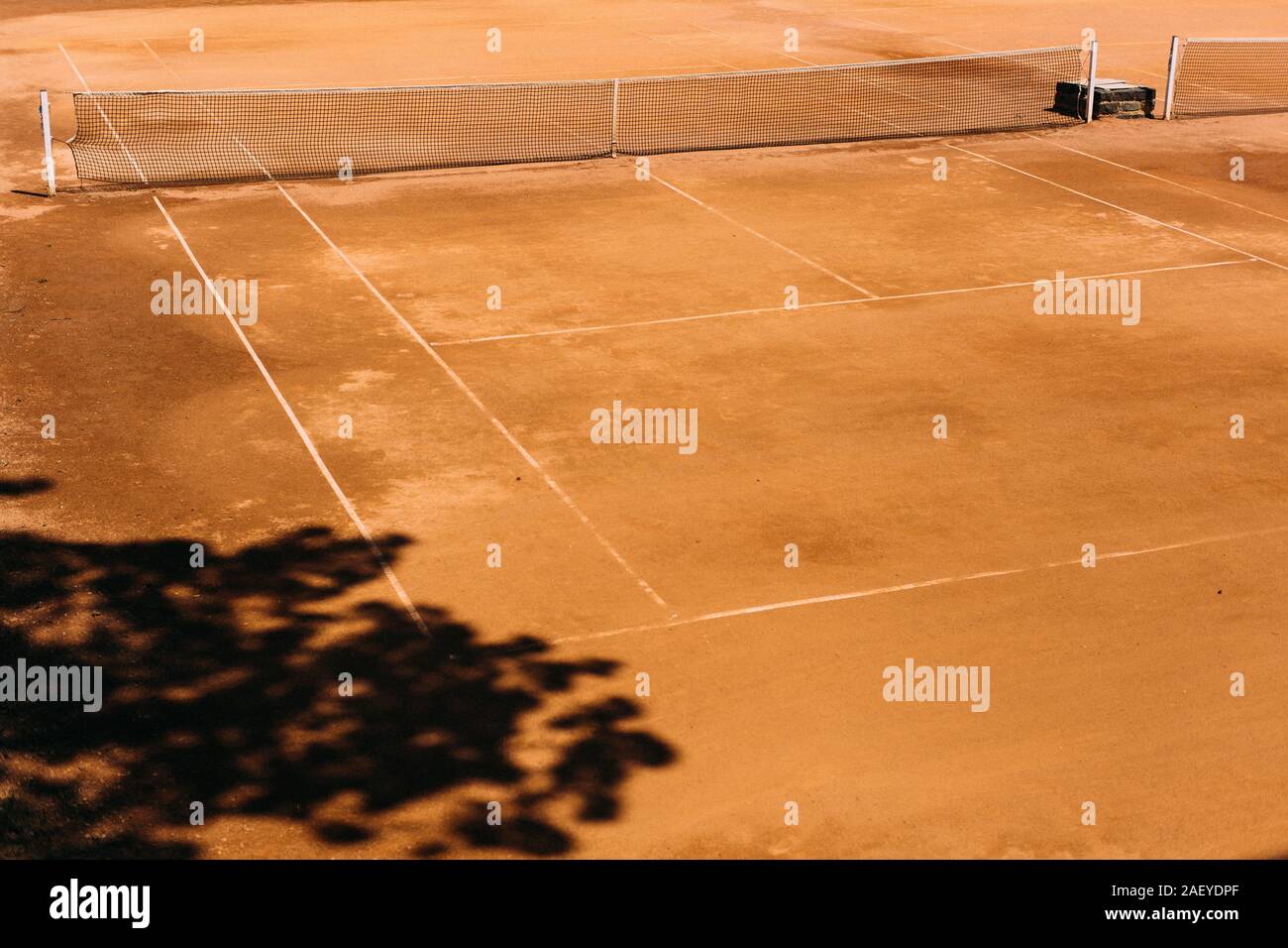 Arancio vecchio campo da tennis con l'ombra di un albero Foto Stock