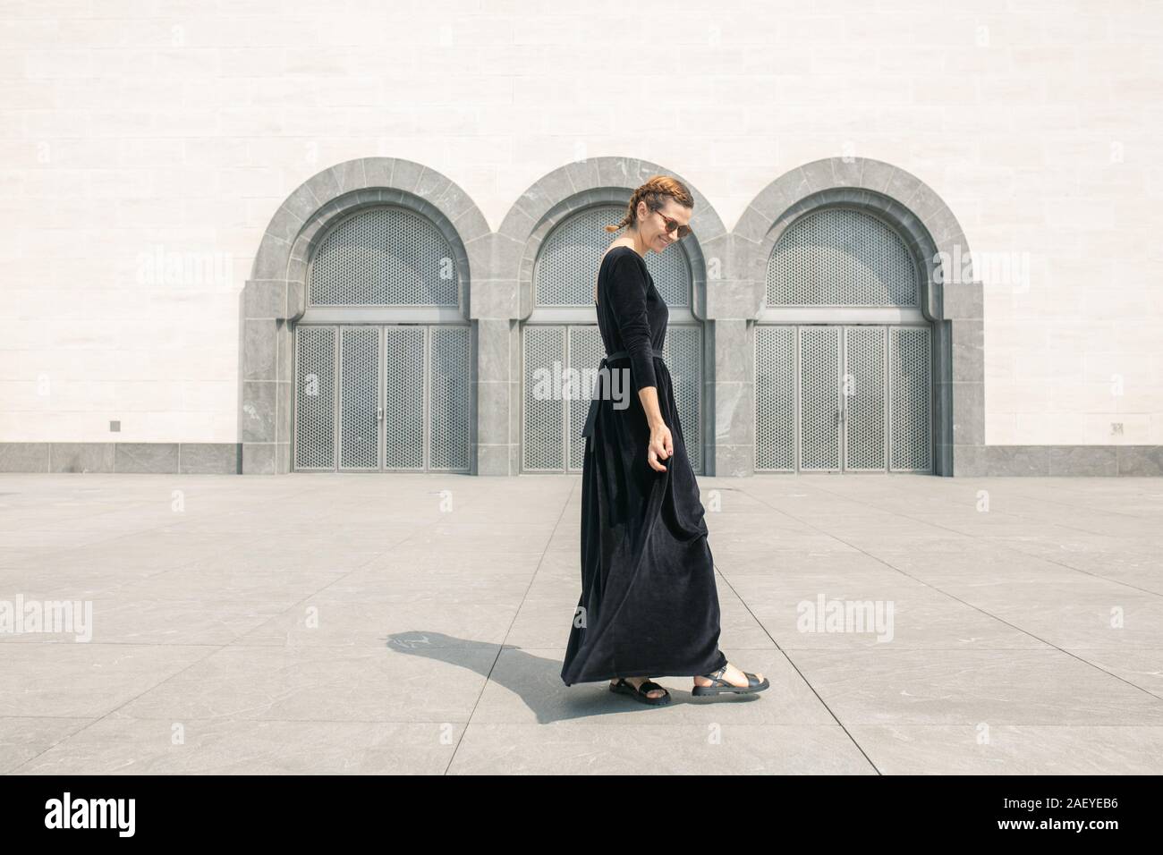 Giovane donna profilo permanente e tenendo premuto il suo abito Foto Stock