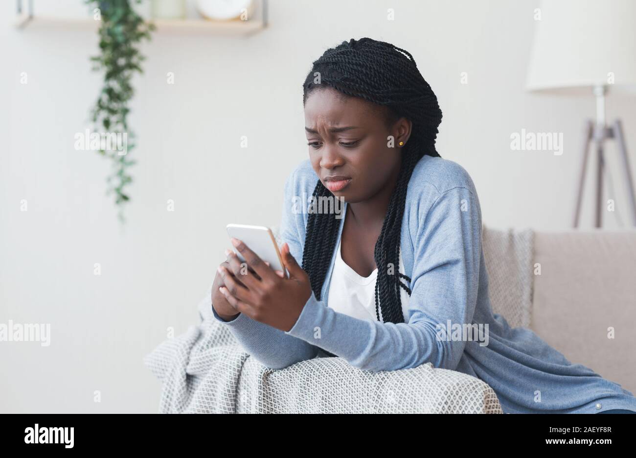 Messaggio errato. Giovane donna nera guardando lo schermo dello smartphone con una faccina triste espressione, spazio libero Foto Stock