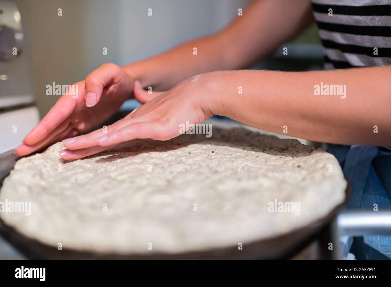 Teglia cotte con impasto per pizza prima della cottura realizzato con senza glutine farina e donna mani crosta di formatura Foto Stock