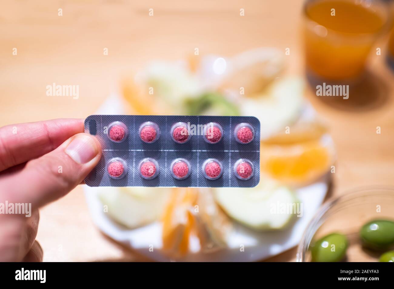 Mano azienda miracolo berry ledidi Synsepalum dulcificum berry tablet confezionati che trasforma gli alimenti agro dolce con cibo in background Foto Stock