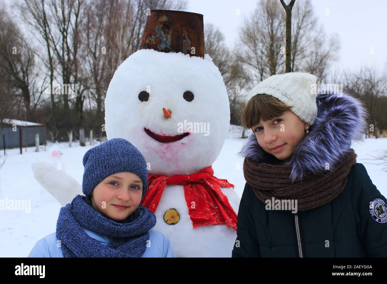 Due sorelle giocare nei pressi di pupazzo di neve nel giorno d'inverno. I bambini fanno pupazzo di neve. Due sorelle rendono pupazzo di neve in inverno giorno Foto Stock