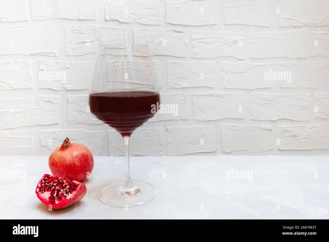 Melograno del vino in un bicchiere di vino su sfondo neutro Foto Stock