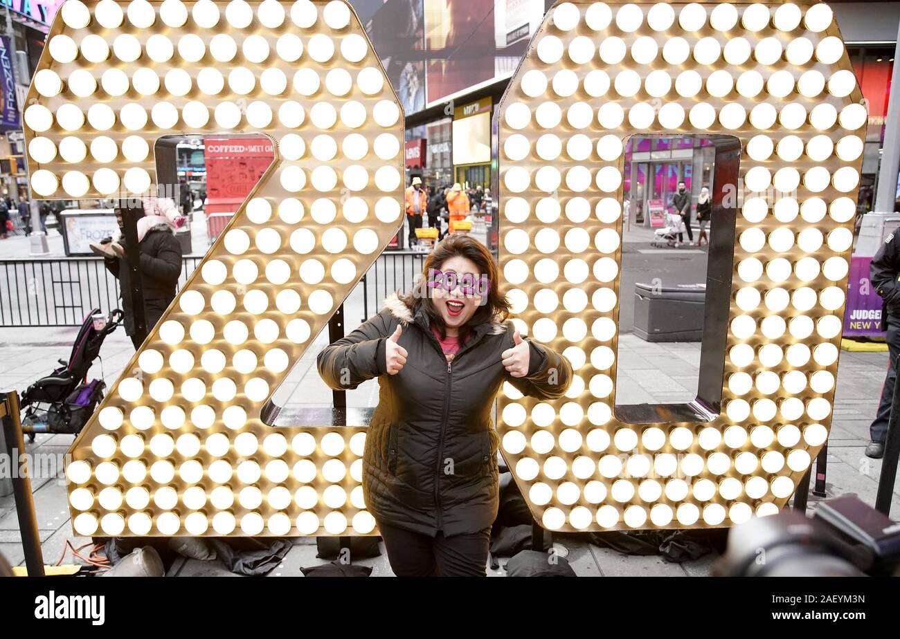 Una donna che indossa gli occhiali 2020 prende una foto infantile permanente dei due e zero del 2020 Capodanno numerici quando sono illuminati in Times Square a New York City il Mercoledì, Dicembre 11, 2019. Il gigante, sette piedi di altezza '20' è arrivato su un autocarro a pianale sulla 46th Street e Broadway e sarà portata alla sommità di una Times Square dove potranno riposare per un paio di giorni prima di completare il '2-0C2-0' segno che illumina a mezzanotte di Capodanno per annunciare l inizio del nuovo anno al completamento della sfera Drop. Foto di Giovanni Angelillo/UPI Foto Stock