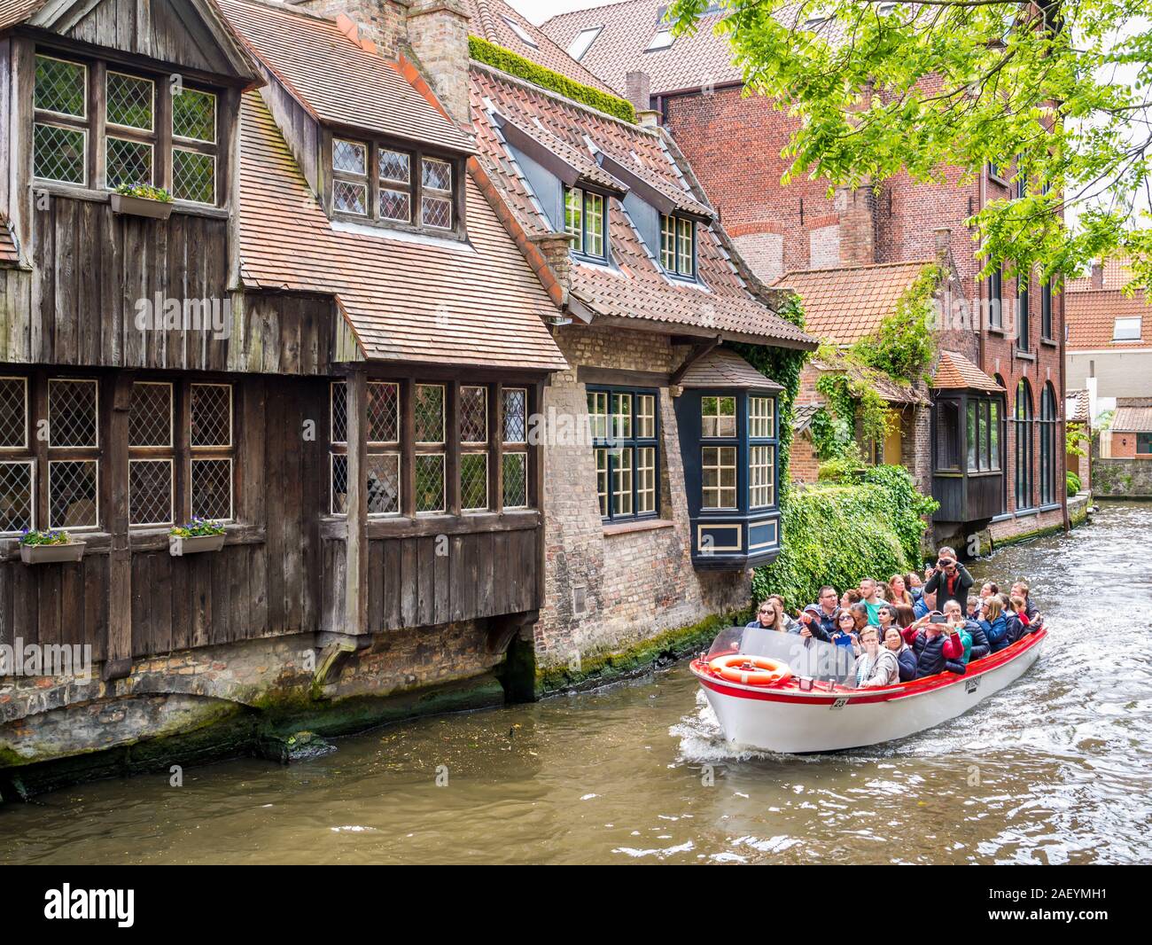 Persone in viaggio in barca sul canale Dijver e case storiche nel centro storico di Bruges, Belgio Foto Stock