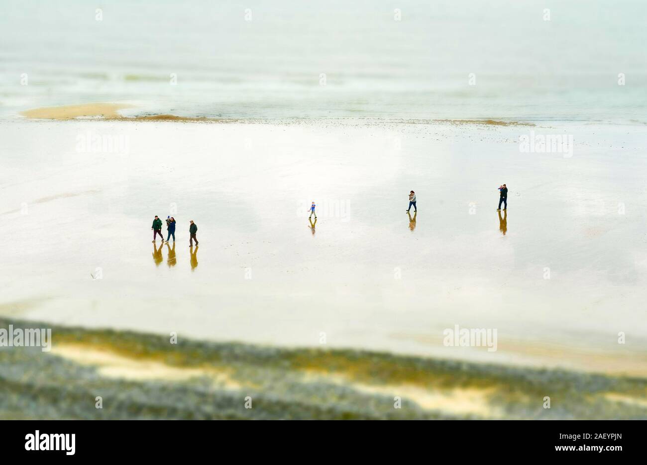 Persone che camminano in lontananza su un'ampia spiaggia di sabbia Foto Stock