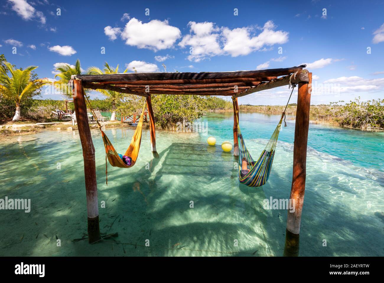 I turisti riposano sulle amache sopra l'acqua azzurra alle rapide vicino a Bacalar, Quintana Roo, Messico. Foto Stock