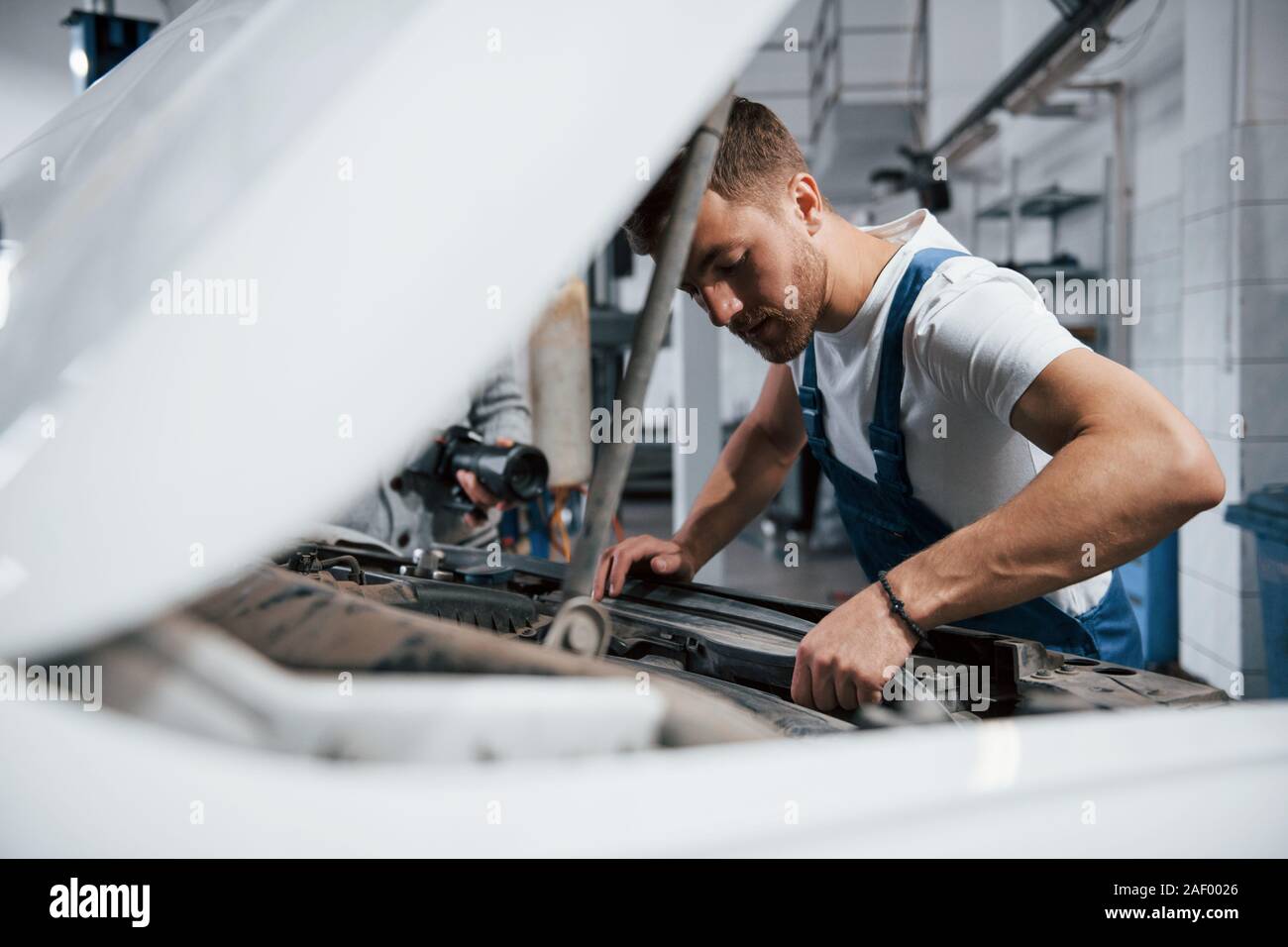 Look concentrato. Il dipendente nel colore blu uniforme di opere in Salon Automobile Foto Stock