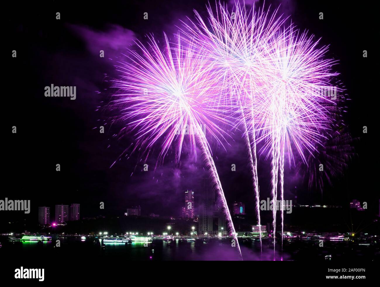 La vibrante rosa e viola di spruzzi di fuochi d'artificio nel cielo notturno sulla città Foto Stock